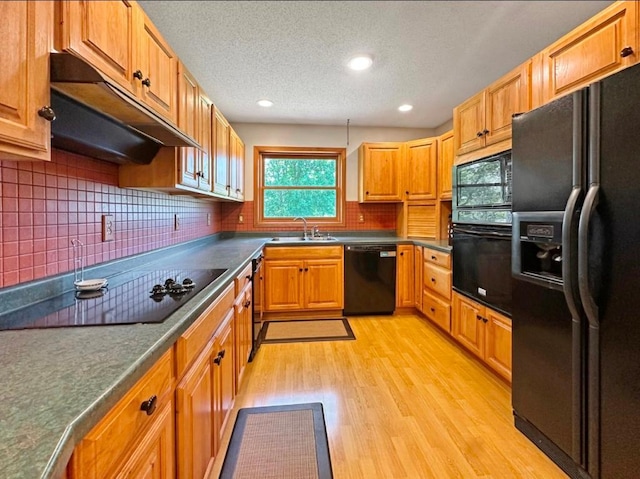 2117 Isleview Rd, Grand Rapids, MN 55744 - kitchen featuring black appliances, under cabinet range hood, light wood-style flooring, dark countertops, and backsplash