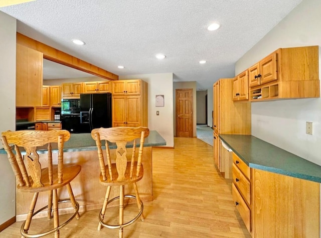 2117 Isleview Rd, Grand Rapids, MN 55744 - kitchen featuring black appliances, a breakfast bar area, light wood-style floors, a peninsula, and a textured ceiling