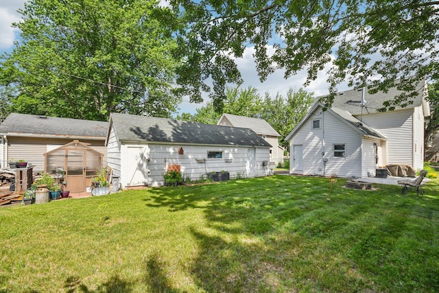 6429 Maple St, North Branch, MN 55056 - rear view of house with an outdoor fire pit, an outdoor structure, a yard, and a greenhouse