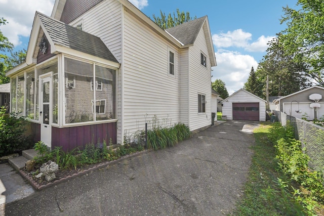 6429 Maple St, North Branch, MN 55056 - view of side of home featuring a sunroom, a detached garage, and a shingled roof