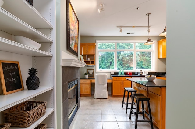 510 Grand Ave Unit 101, Saint Paul, MN 55102 - kitchen with dark countertops, a fireplace, open shelves, light tile patterned floors, and hanging light fixtures