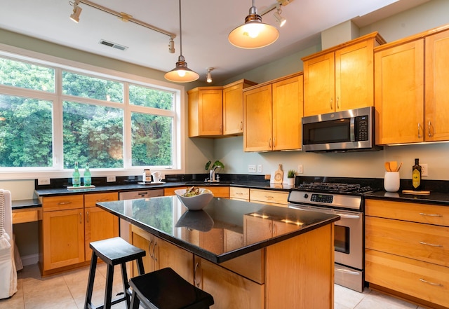 510 Grand Ave Unit 101, Saint Paul, MN 55102 - kitchen featuring stainless steel appliances, rail lighting, light tile patterned floors, and a kitchen island
