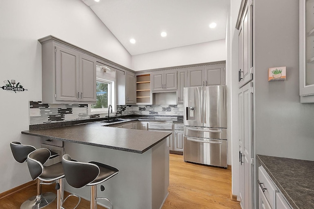 1219 Lakeview Pkwy, Buffalo, MN 55313 - kitchen with stainless steel refrigerator with ice dispenser, dark countertops, gray cabinets, a peninsula, and vaulted ceiling
