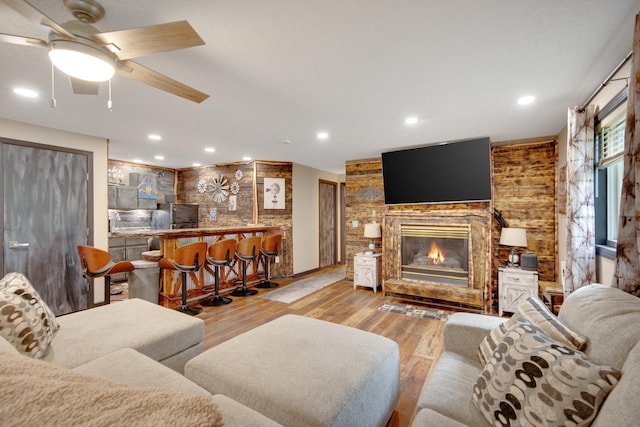 1219 Lakeview Pkwy, Buffalo, MN 55313 - living room featuring wood finished floors, a glass covered fireplace, ceiling fan, a bar, and recessed lighting