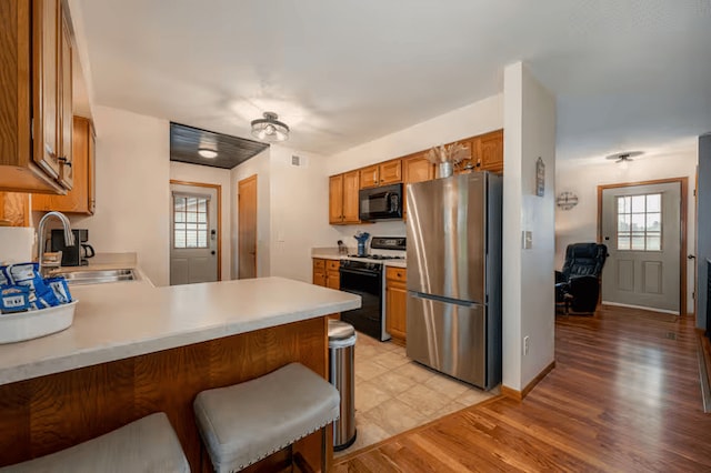 25463 County Road 267, Cohasset, MN 55721 - kitchen with freestanding refrigerator, range with gas stovetop, black microwave, light countertops, and a peninsula