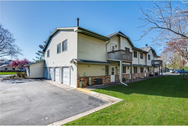 11348 Ibis St NW, Coon Rapids, MN 55433 - rear view of property with a garage, a yard, asphalt driveway, brick siding, and a balcony