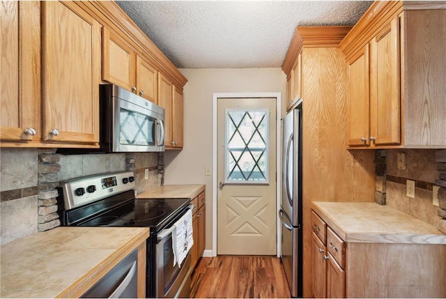 11348 Ibis St NW, Coon Rapids, MN 55433 - kitchen featuring stainless steel appliances, light countertops, backsplash, wood finished floors, and a textured ceiling