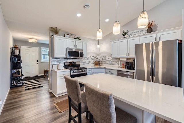 6908 101st St S, Cottage Grove, MN 55016 - kitchen with stainless steel appliances, tasteful backsplash, light countertops, a kitchen breakfast bar, and dark wood finished floors