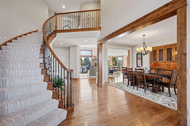 7530 Quail Ridge Trl, Greenfield, MN 55373 - dining room featuring stairs, wood finished floors, a chandelier, a high ceiling, and recessed lighting