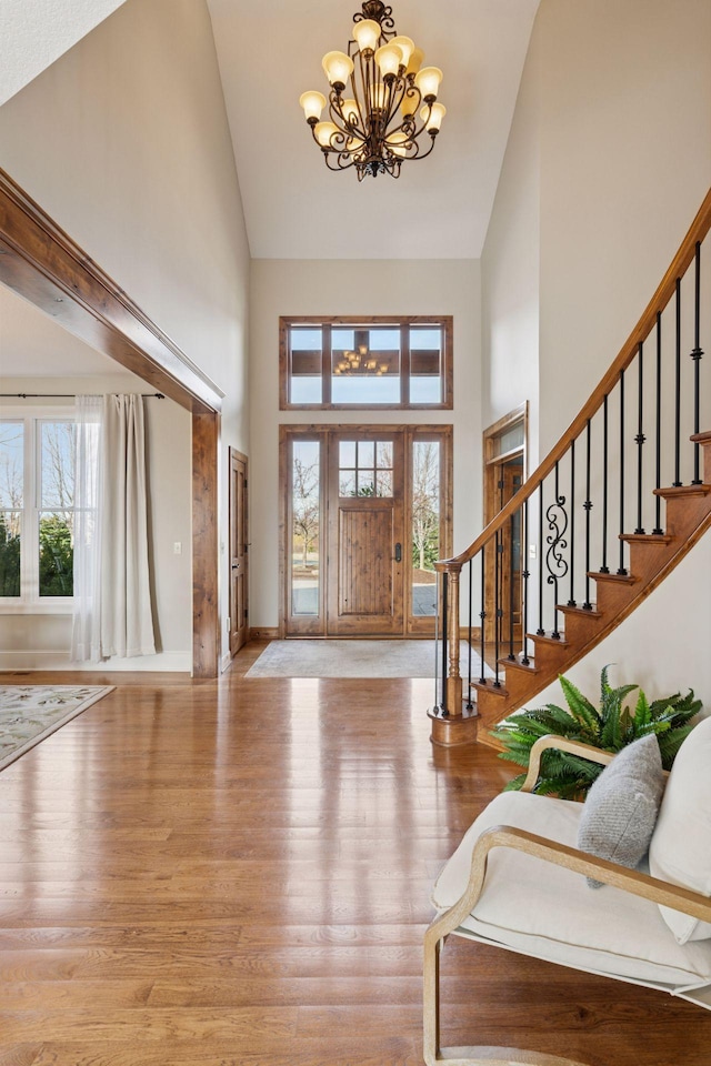 7530 Quail Ridge Trl, Greenfield, MN 55373 - foyer entrance with high vaulted ceiling, a chandelier, stairs, wood finished floors, and healthy amount of natural light
