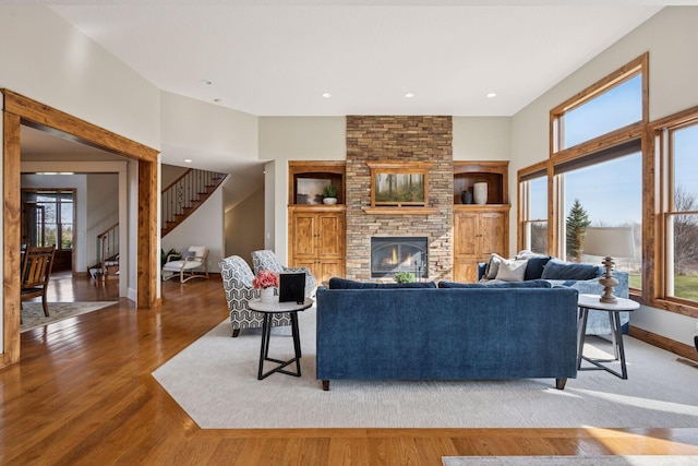 7530 Quail Ridge Trl, Greenfield, MN 55373 - living room featuring stairs, built in shelves, a large fireplace, and wood finished floors