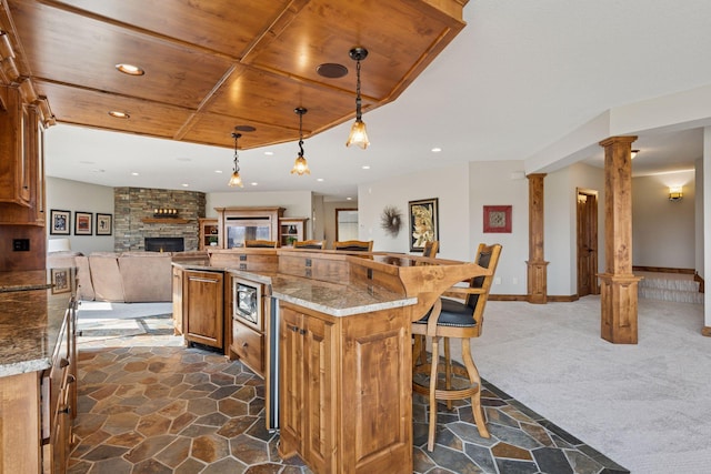 7530 Quail Ridge Trl, Greenfield, MN 55373 - kitchen featuring open floor plan, ornate columns, wooden ceiling, stone floors, and brown cabinets