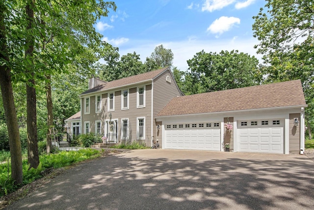 2261 Ash St, Lino Lakes, MN 55110 - colonial home featuring a chimney, driveway, an attached garage, and a shingled roof