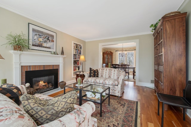 2261 Ash St, Lino Lakes, MN 55110 - living area with wood finished floors, ornamental molding, a chandelier, and a brick fireplace