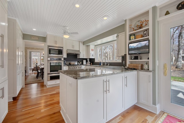 2261 Ash St, Lino Lakes, MN 55110 - kitchen featuring stainless steel appliances, a peninsula, dark stone countertops, light wood-style floors, and white cabinetry