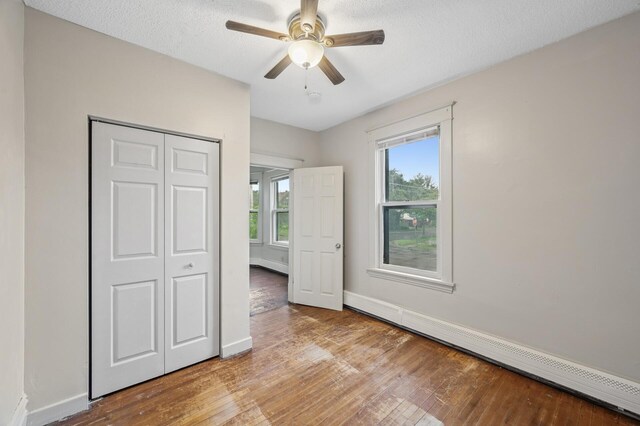 61 Delos St W, Saint Paul, MN 55107 - unfurnished bedroom featuring baseboard heating, hardwood / wood-style floors, a closet, and a textured ceiling