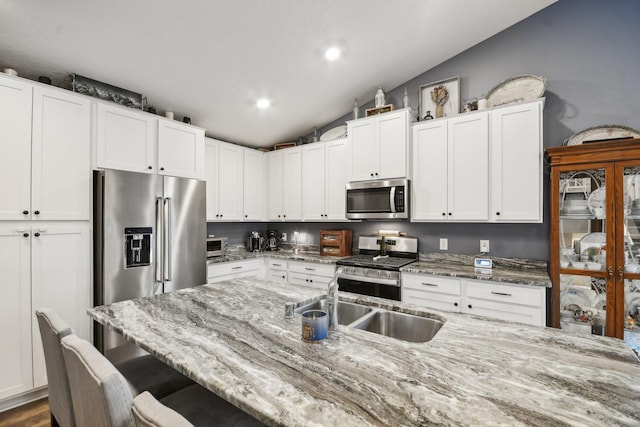 7516 Ochoa Ave NE, Otsego, MN 55330 - kitchen featuring stainless steel appliances, a kitchen bar, lofted ceiling, white cabinets, and light stone counters
