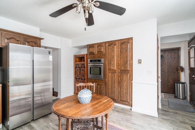 217 6th St, Crookston, MN 56716 - kitchen featuring stainless steel appliances, light wood finished floors, a ceiling fan, and brown cabinets