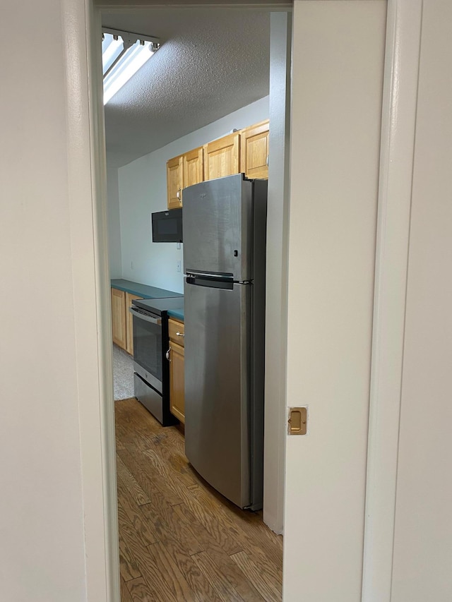 10113 34th St Unit 335, Minnetonka, MN 55305 - kitchen with stainless steel appliances, wood finished floors, dark countertops, light brown cabinetry, and a textured ceiling