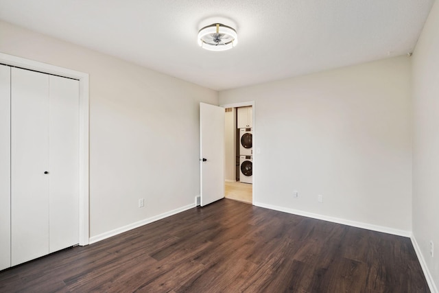 434 11th St Unit D, New Richmond, WI 54017 - unfurnished bedroom with stacked washer and clothes dryer, dark wood-style floors, and a closet