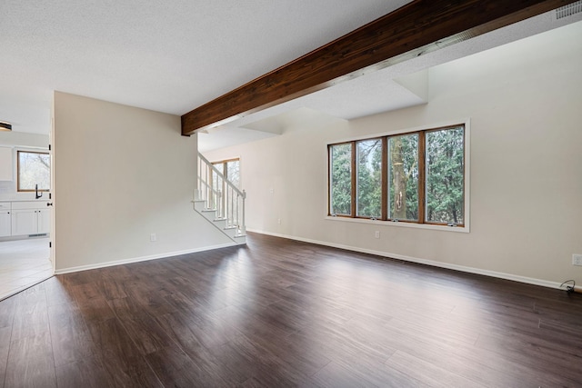 434 11th St Unit D, New Richmond, WI 54017 - unfurnished living room with dark wood finished floors, stairs, and beam ceiling