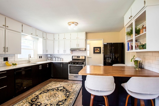 311 Fremont St, River Falls, WI 54022 - kitchen with black appliances, under cabinet range hood, decorative backsplash, white cabinets, and dark cabinetry