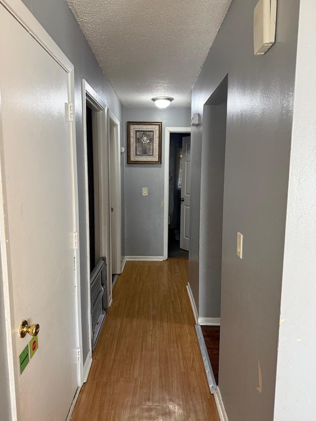 8208 Halifax Ct N, Brooklyn Park, MN 55443 - hallway featuring wood finished floors, a textured ceiling, and heating unit