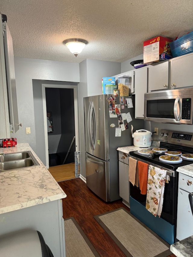8208 Halifax Ct N, Brooklyn Park, MN 55443 - kitchen featuring stainless steel appliances, light countertops, dark wood-type flooring, and a textured ceiling