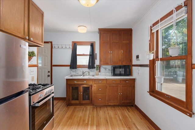 3506 Boardman St, Minneapolis, MN 55417 - kitchen with appliances with stainless steel finishes, light wood-style floors, brown cabinetry, light countertops, and crown molding