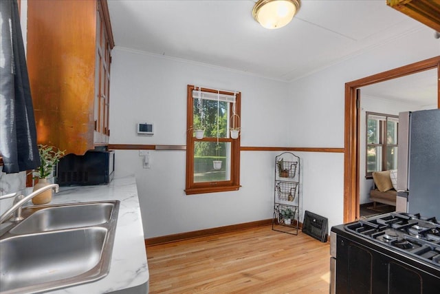 3506 Boardman St, Minneapolis, MN 55417 - kitchen with freestanding refrigerator, range with gas stovetop, plenty of natural light, light wood-style floors, and crown molding