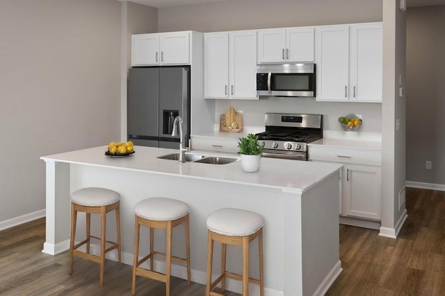 7861 Ramsey Pkwy NW, Ramsey, MN 55303 - kitchen featuring appliances with stainless steel finishes, dark wood-style floors, white cabinetry, light countertops, and a kitchen island with sink