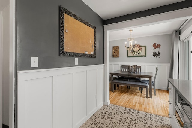 771 Creek Ave, Mendota Heights, MN 55120 - dining space with a chandelier, crown molding, light tile patterned floors, wainscoting, and a decorative wall