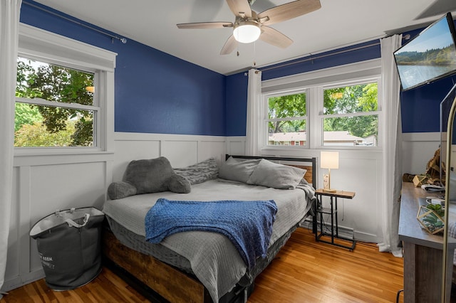 771 Creek Ave, Mendota Heights, MN 55120 - bedroom with a wainscoted wall, multiple windows, wood finished floors, a decorative wall, and a ceiling fan