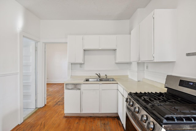 104 27th St, Minneapolis, MN 55408 - kitchen featuring stainless steel gas range oven, light countertops, white cabinetry, and wood-type flooring