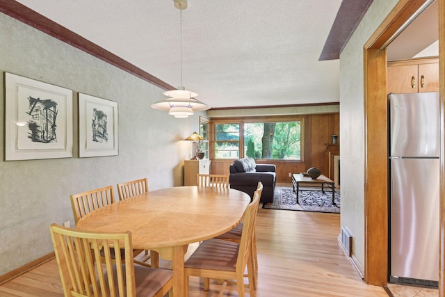 3748 Hilltop Rd, Minnetonka, MN 55305 - dining room featuring light wood-style floors, a textured ceiling, a textured wall, and crown molding
