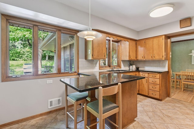 3748 Hilltop Rd, Minnetonka, MN 55305 - kitchen with tasteful backsplash, brown cabinetry, a peninsula, decorative light fixtures, and a kitchen breakfast bar