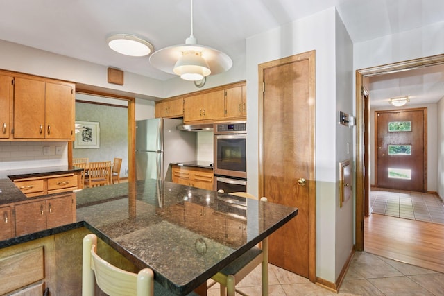 3748 Hilltop Rd, Minnetonka, MN 55305 - kitchen with light tile patterned flooring, appliances with stainless steel finishes, decorative backsplash, dark stone countertops, and brown cabinets