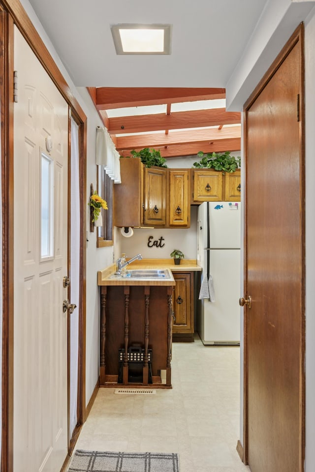 2921 Cambridge Ln, Mound, MN 55364 - kitchen featuring freestanding refrigerator, brown cabinets, a peninsula, beam ceiling, and light flooring