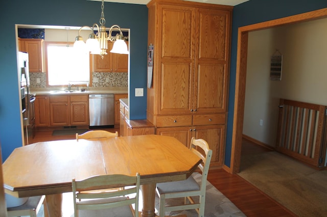 1508 6th Ave S, Sartell, MN 56377 - kitchen with stainless steel dishwasher, a chandelier, wood finished floors, tasteful backsplash, and light countertops