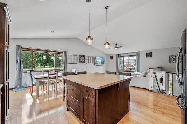 22493 Carina Ct, Farmington, MN 55024 - kitchen featuring a ceiling fan, light wood-style floors, dark brown cabinets, freestanding refrigerator, and lofted ceiling