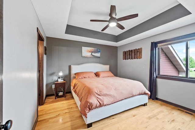 22493 Carina Ct, Farmington, MN 55024 - bedroom featuring a tray ceiling, light wood-style flooring, and ceiling fan