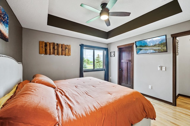 22493 Carina Ct, Farmington, MN 55024 - bedroom featuring a tray ceiling, light wood-type flooring, and a ceiling fan