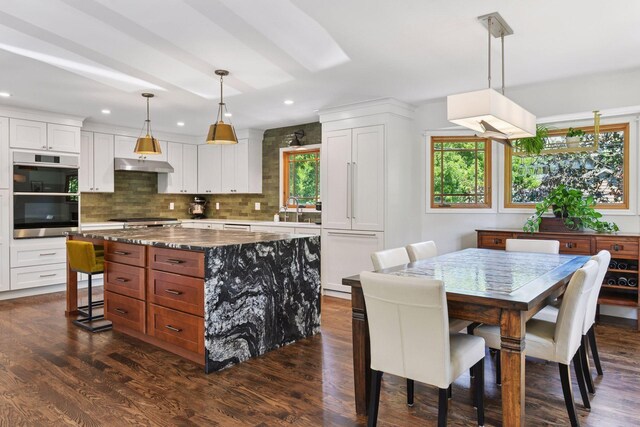 4011 Grimes Ave S, Edina, MN 55416 - kitchen featuring under cabinet range hood, white cabinets, a center island, dark wood finished floors, and recessed lighting