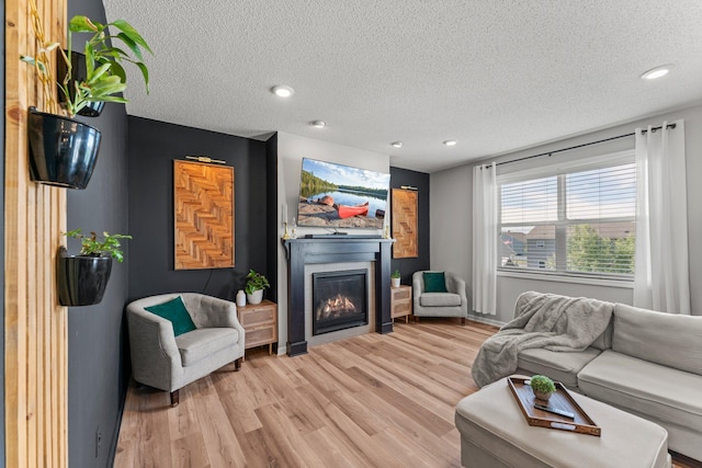 1174 139th St E, Rosemount, MN 55068 - living room featuring a glass covered fireplace, a textured ceiling, light wood-style floors, and recessed lighting
