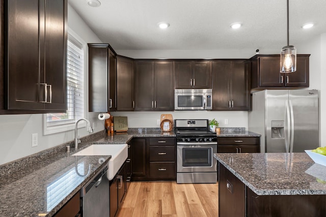 1174 139th St E, Rosemount, MN 55068 - kitchen with stainless steel appliances, dark brown cabinets, light wood finished floors, dark stone counters, and recessed lighting