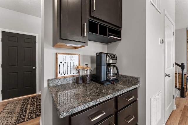 1174 139th St E, Rosemount, MN 55068 - kitchen featuring light wood-style flooring, dark brown cabinetry, dark stone counters, and a textured ceiling