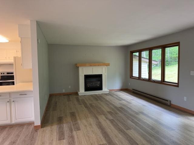 240 12th Ave, Grand Rapids, MN 55744 - unfurnished living room featuring a baseboard heating unit, wood finished floors, and a glass covered fireplace