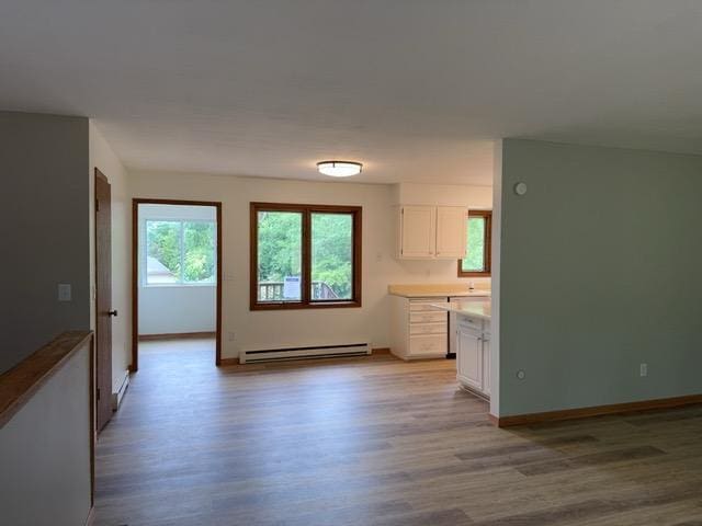 240 12th Ave, Grand Rapids, MN 55744 - kitchen with a baseboard radiator, light wood-style flooring, white cabinetry, and light countertops