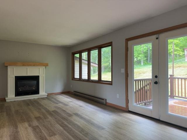 240 12th Ave, Grand Rapids, MN 55744 - unfurnished living room featuring a baseboard radiator, wood finished floors, french doors, and a glass covered fireplace
