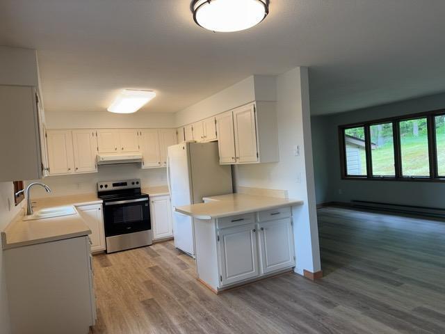 240 12th Ave, Grand Rapids, MN 55744 - kitchen with stainless steel electric range oven, under cabinet range hood, freestanding refrigerator, light wood-style floors, and light countertops